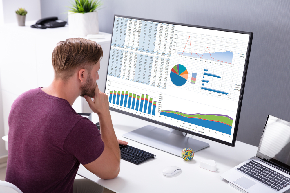 man studying a computer screen with graphs and data