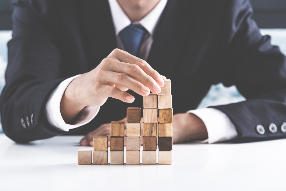 successful business man stacking wooden blocks to form a structure