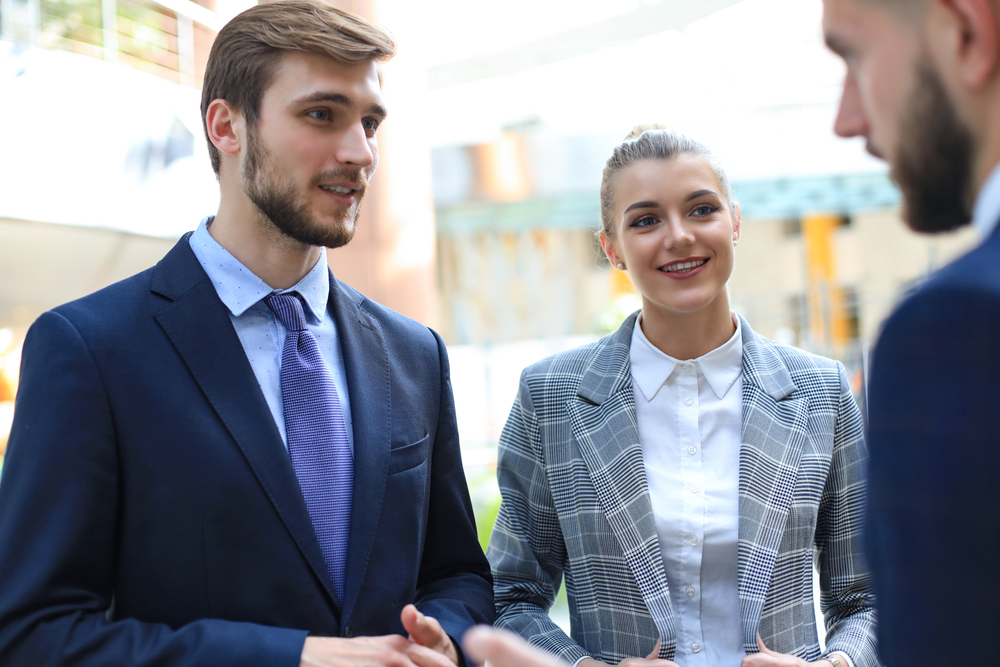 group of three successful employees have a conversation in front of an office building