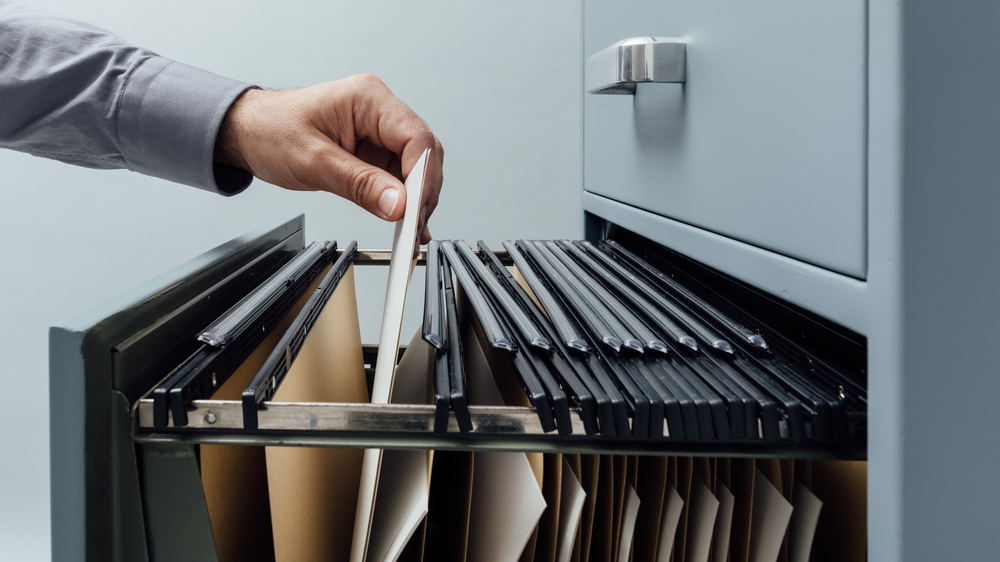 person pulling a file out of a filing cabinet