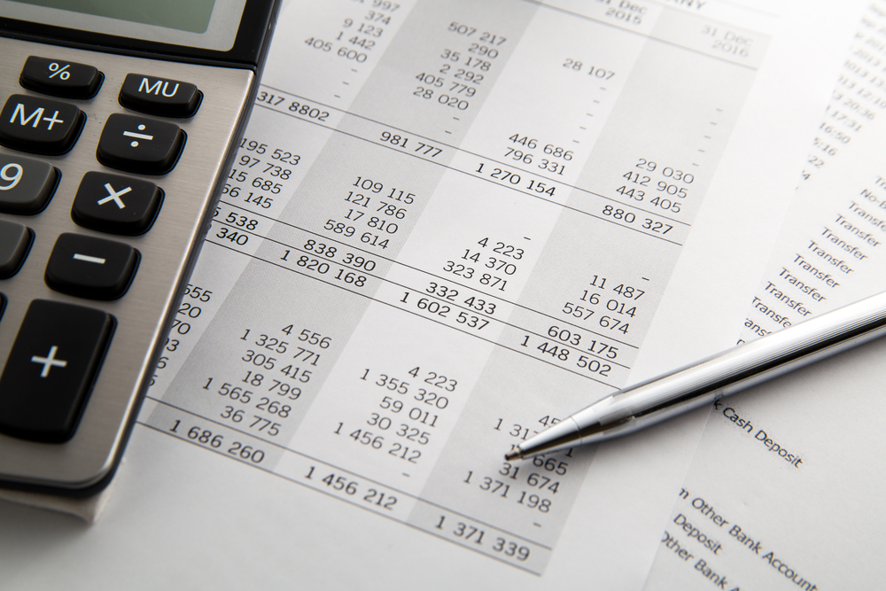 paper with accounting financial statements on a desk with a calculator and a pen