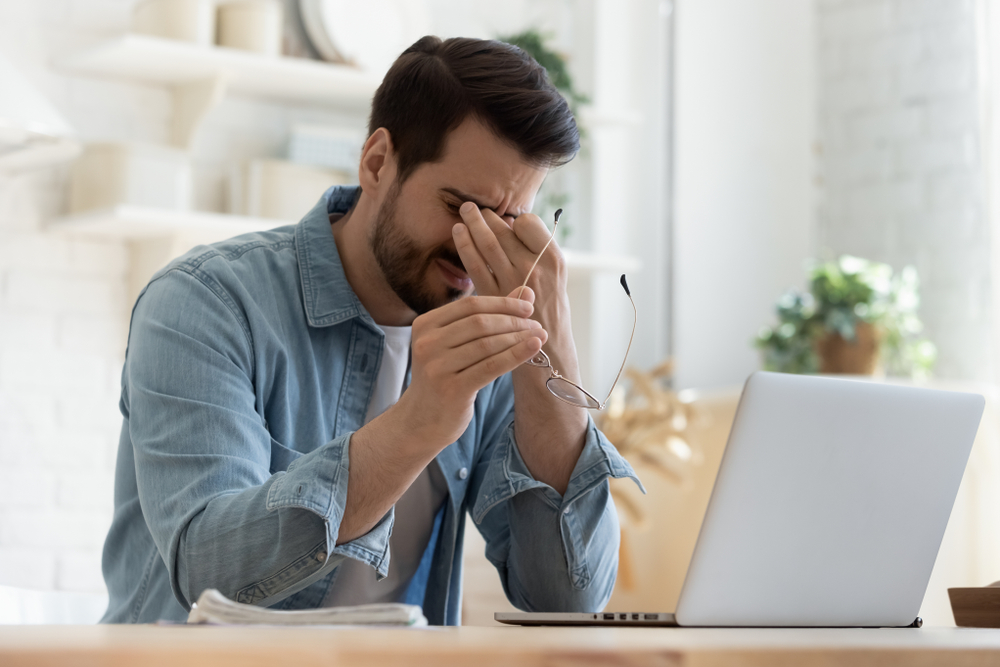 man rubbing his eyes appearing stressed